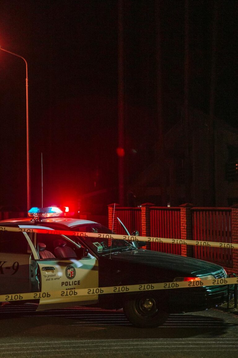 Police car with flashing lights at nighttime accident scene with caution tape