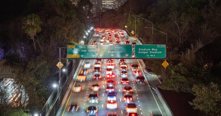 Night traffic on Los Angeles freeway with skyline view