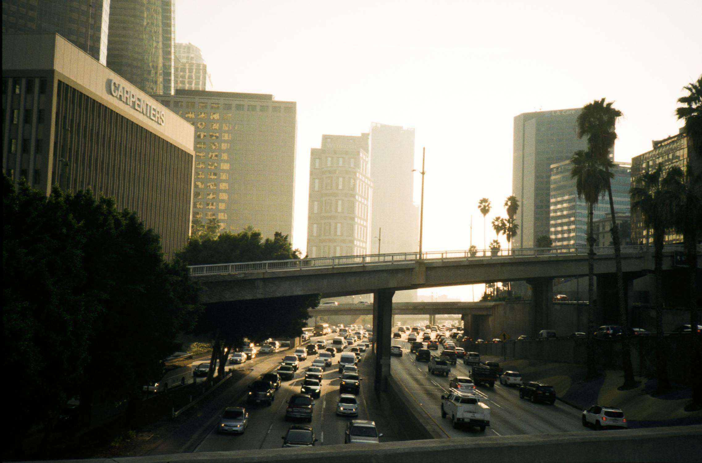 Los Angeles freeway traffic at sunset with palm trees and buildings