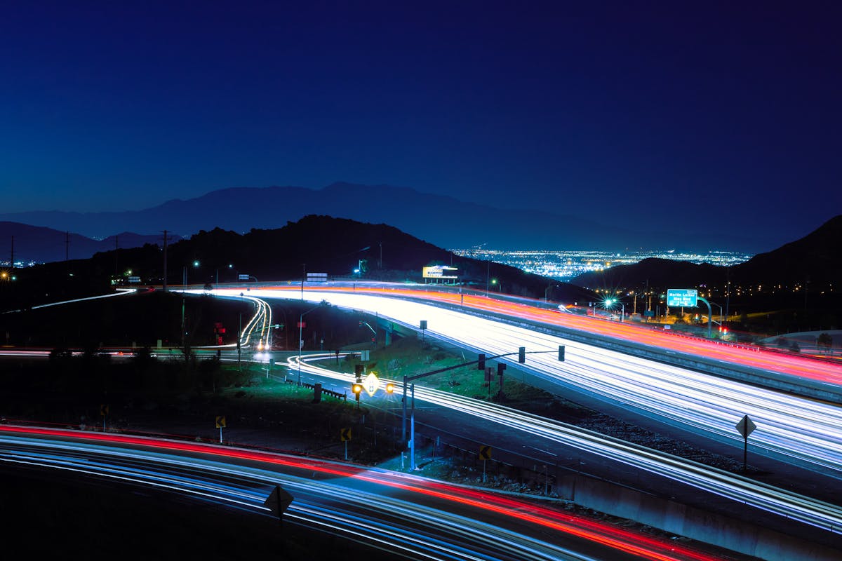 Highway light trails at night in Riverside, California with mountain backdrop