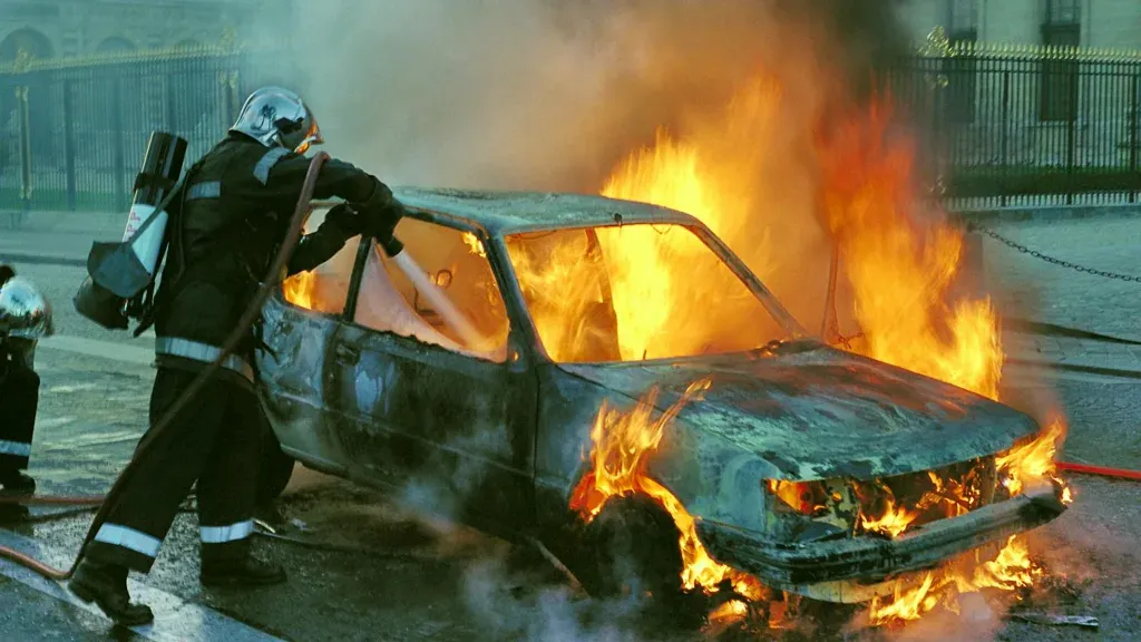 Firefighter extinguishing a burning car after a serious accident